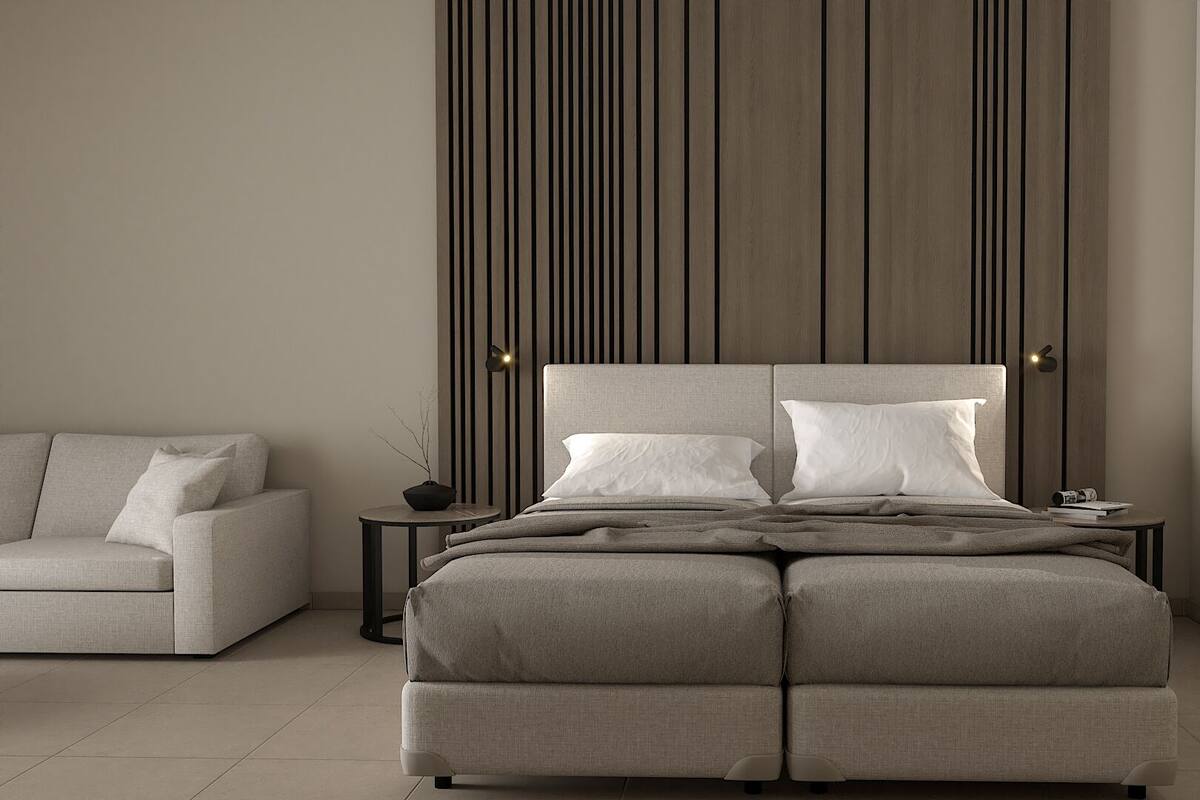 Een moderne slaapkamer met een groot bed, een bank en een muur met verticale lijnen.