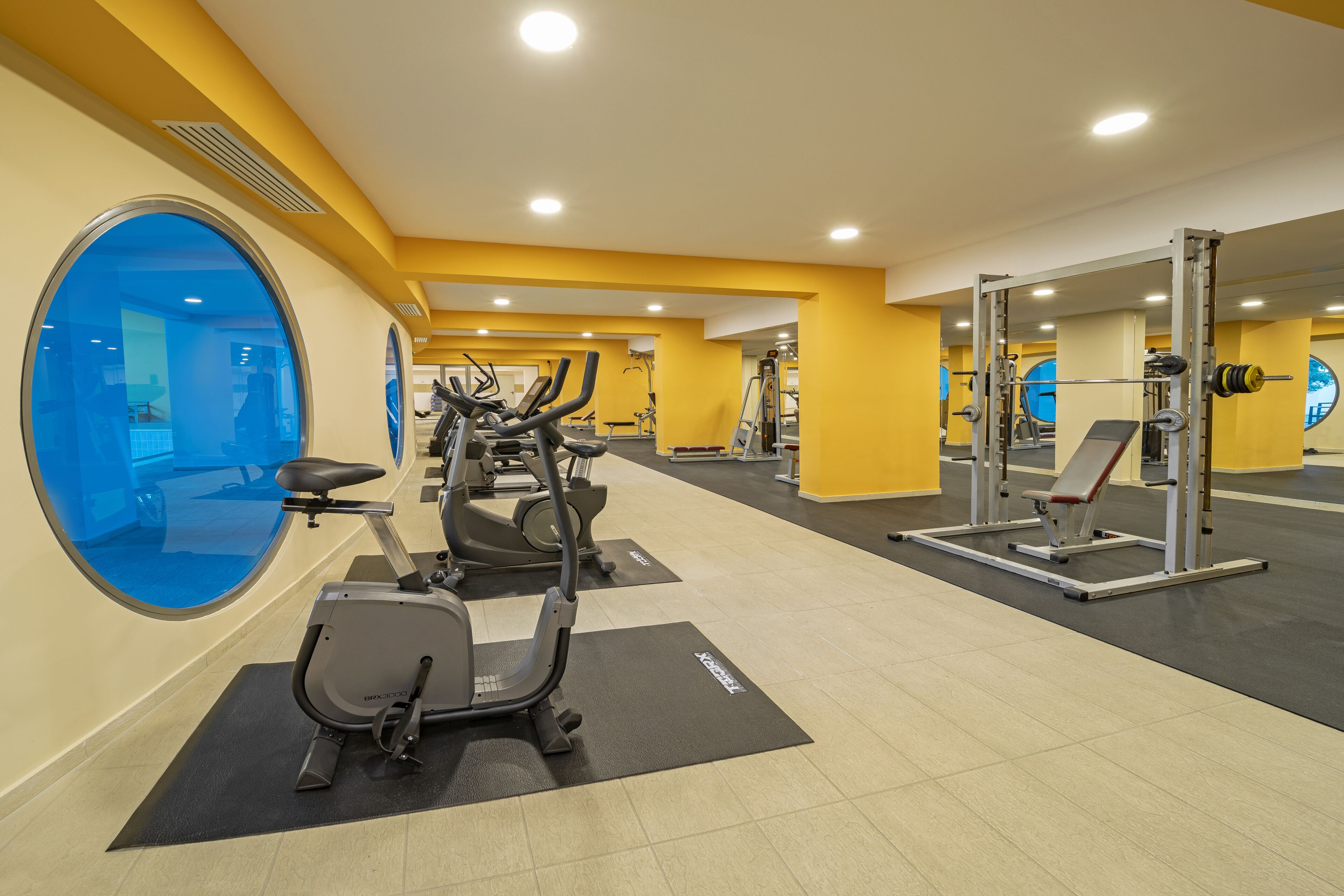 A gym with cardio machines, weightlifting equipment, and mirrored walls.