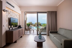 Ein modernes Wohnzimmer mit Sofa, Couchtisch, Fernseher und Blick auf Pool und Grünflächen.