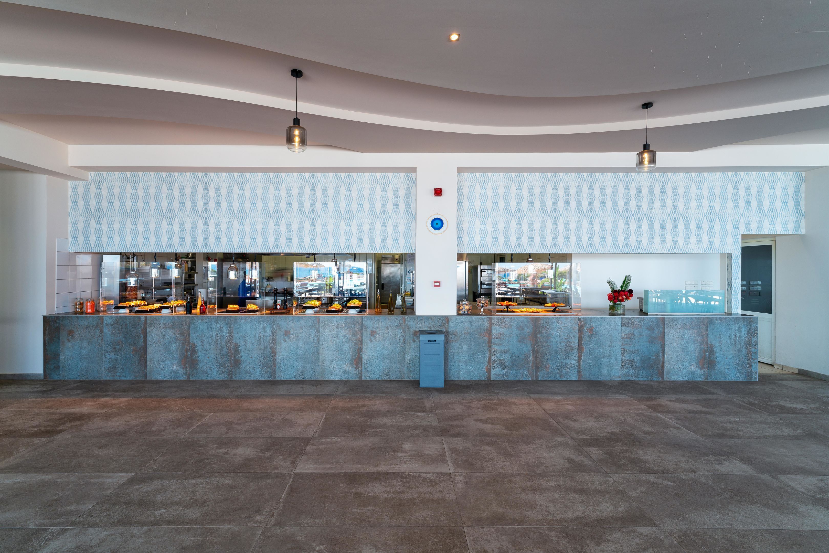 A spacious lobby with a central reception desk, patterned wall tiles, and a tiled floor.