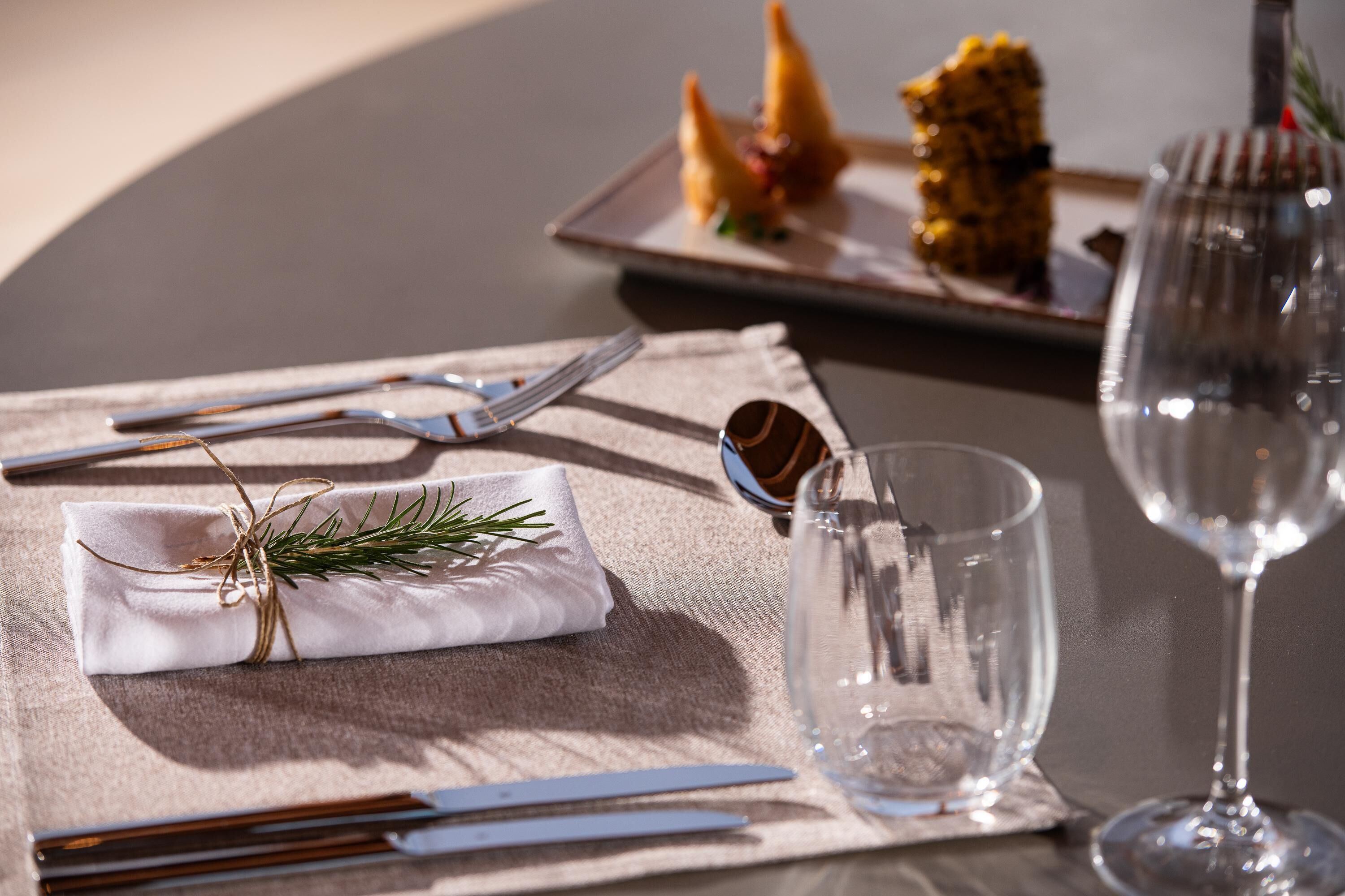 A table set with a folded napkin, silverware, a glass, and a wine glass.
