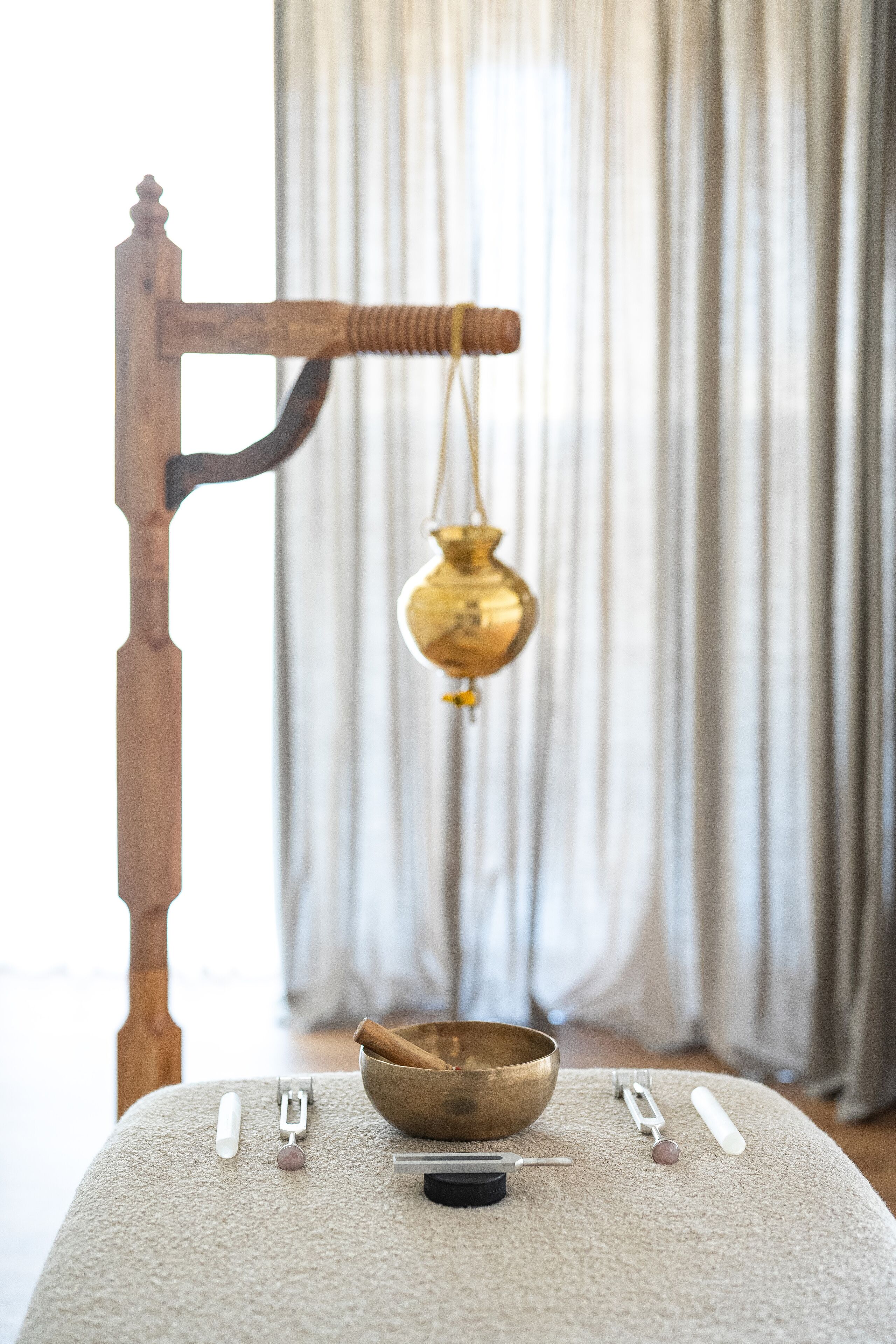 A brass bowl on a table with a wooden stand, a white object, and a small container.