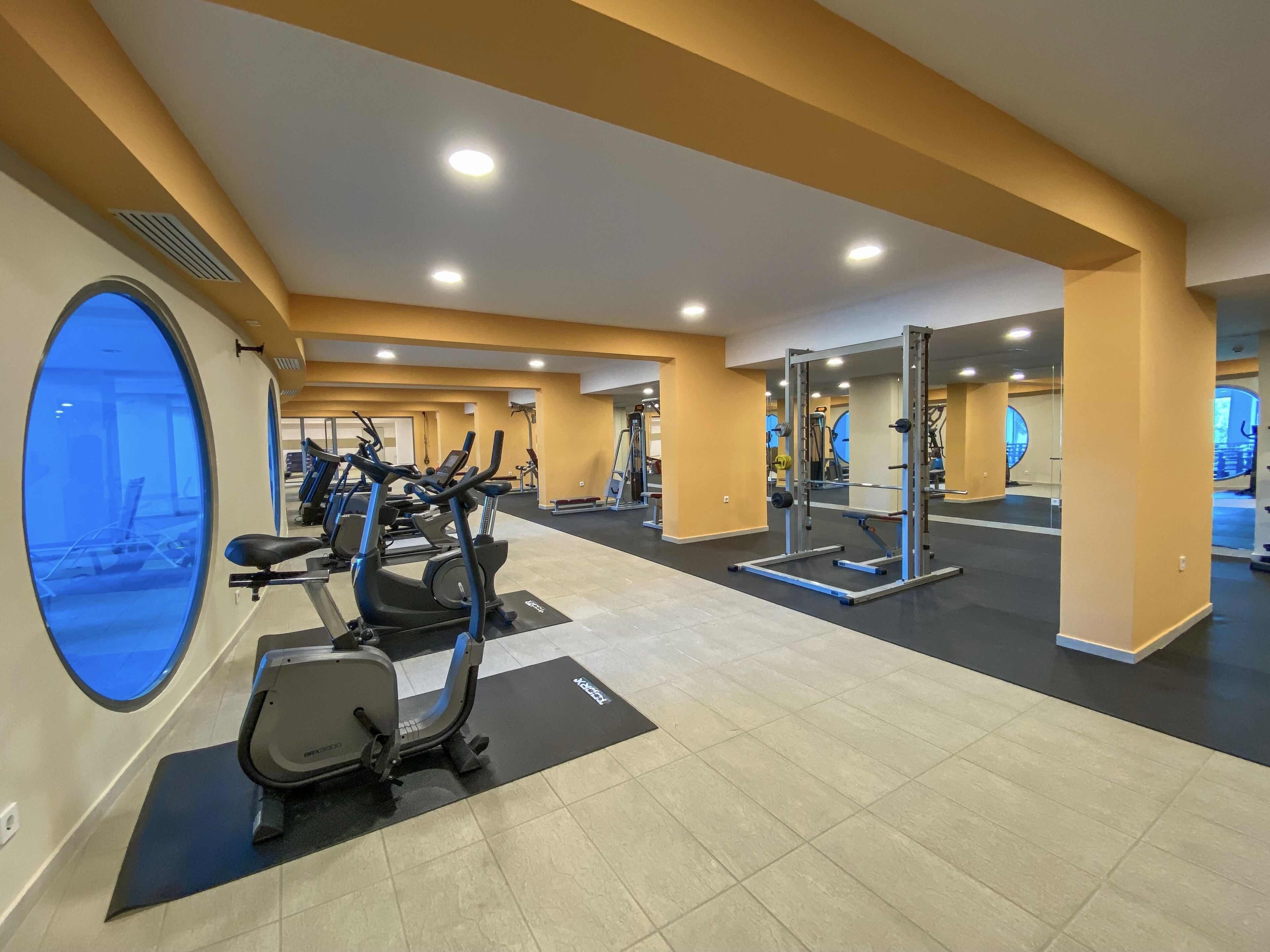 A gym with cardio machines, weightlifting equipment, and mirrors.