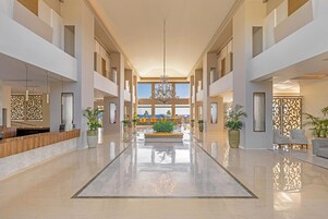 Um hall amplo com área de estar central, janelas grandes e um lustre.