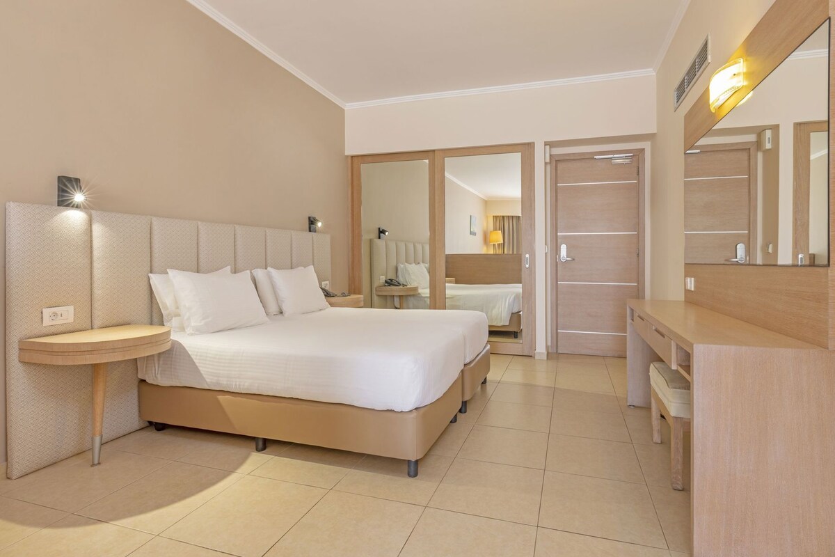 Una habitación de hotel con cama, mesita de noche, espejo y vestidor.