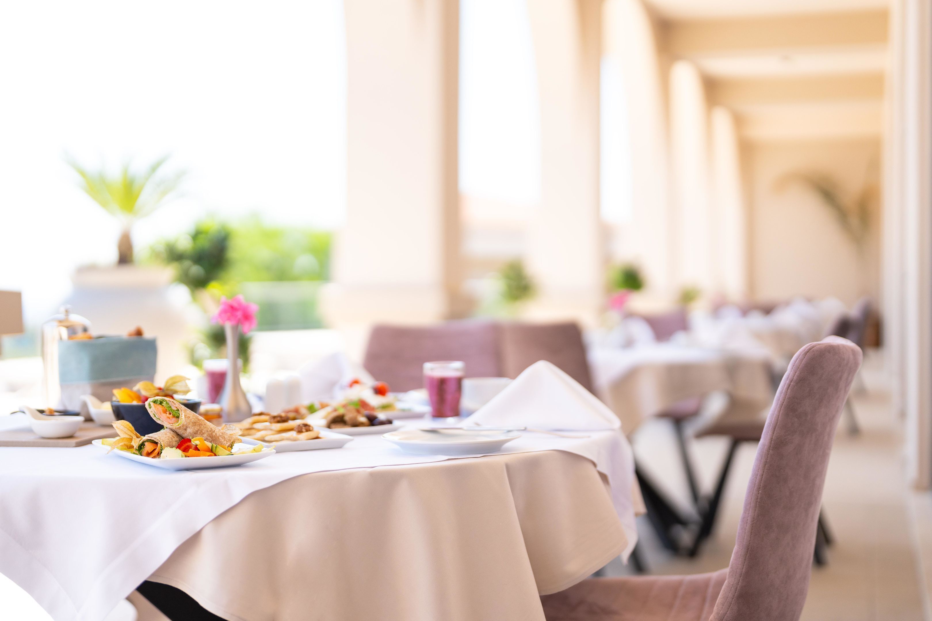 A dining table set with plates of food, a napkin, and a glass of beverage.