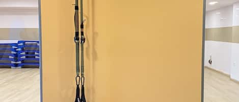 Una habitación con una pared amarilla, una banda de ejercicio negra y tres pelotas de ejercicio.