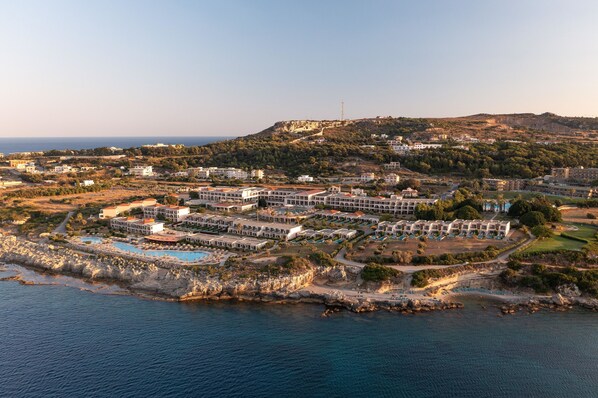 Un resort con varias edificaciones, una piscina y vista al litoral.