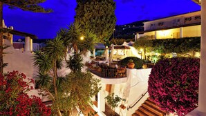 A multi-level outdoor terrace with seating areas, surrounded by lush greenery and flowering plants. - Gattopardo Park Hotel (Lipari)