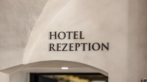 A hotel reception area with a sign indicating "HOTEL RECEPTION" and a lift symbol. - Weisses Roessl Innsbruck GmbH (Innsbruck)