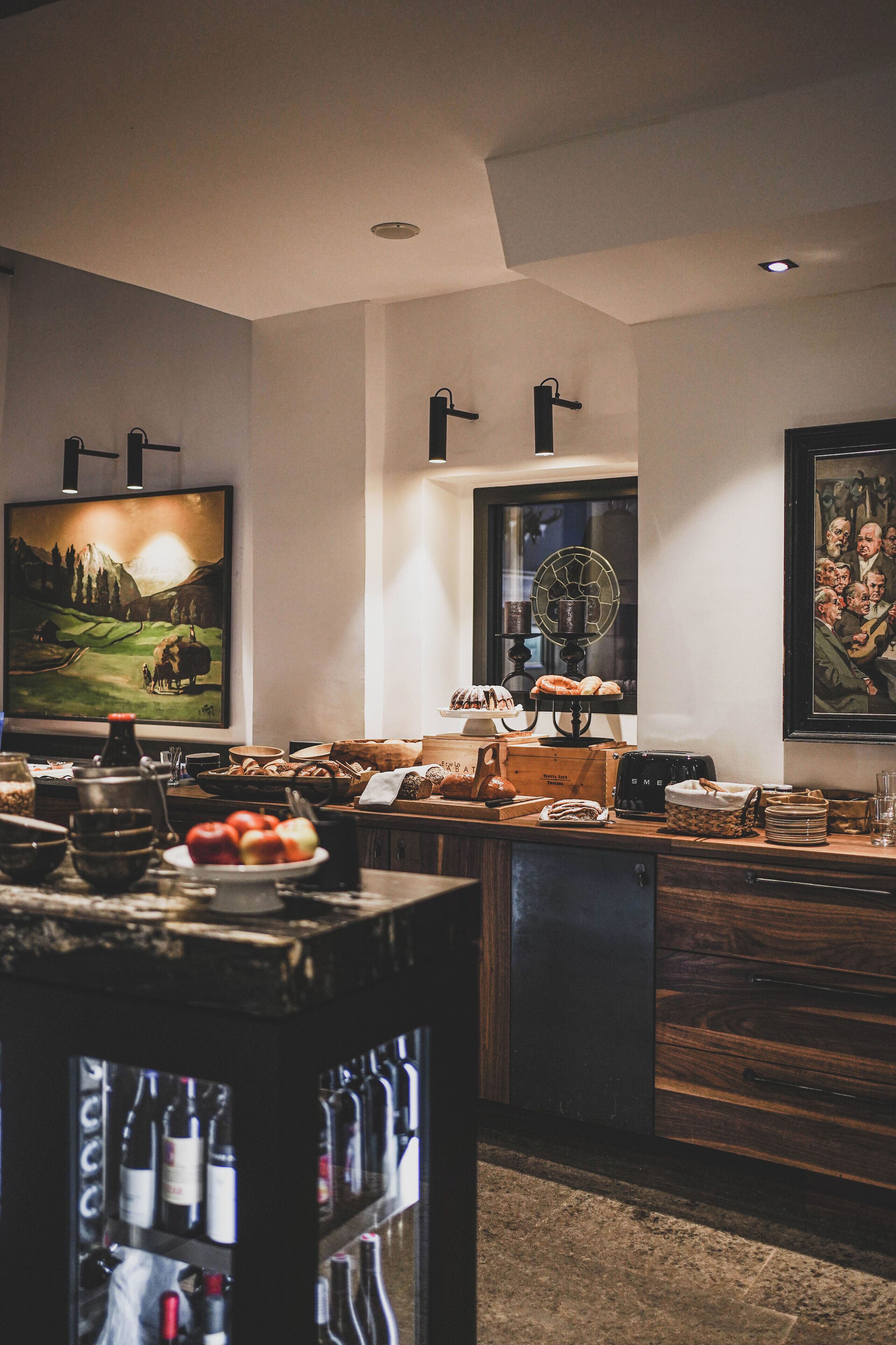 A modern kitchen with a wine rack, a large painting, and a dining area with a table set for a meal.
