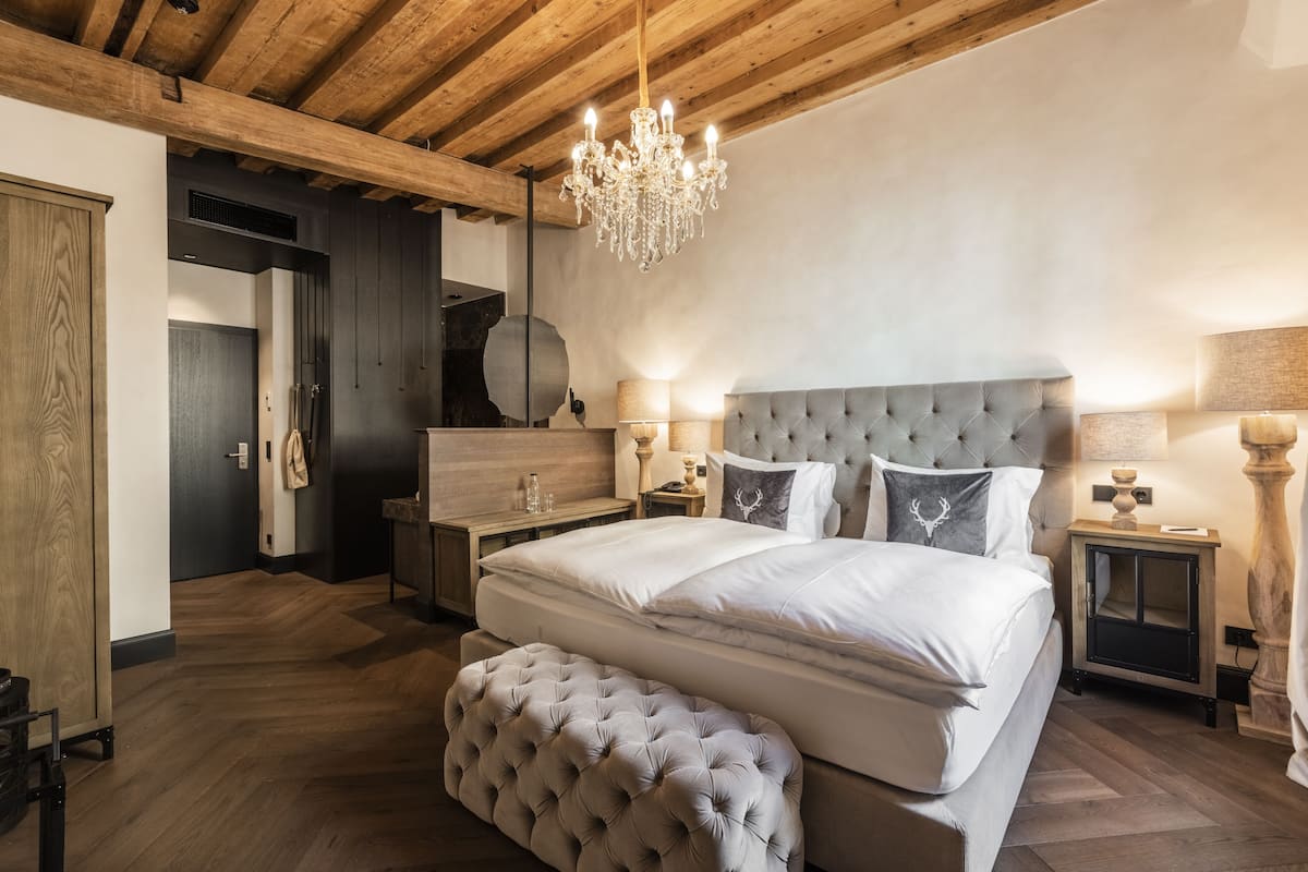 Quarto com uma cama grande, um lustre e teto de madeira.