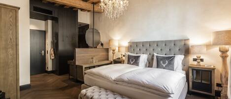 Un dormitorio con una cama grande, una araña y techo de madera.