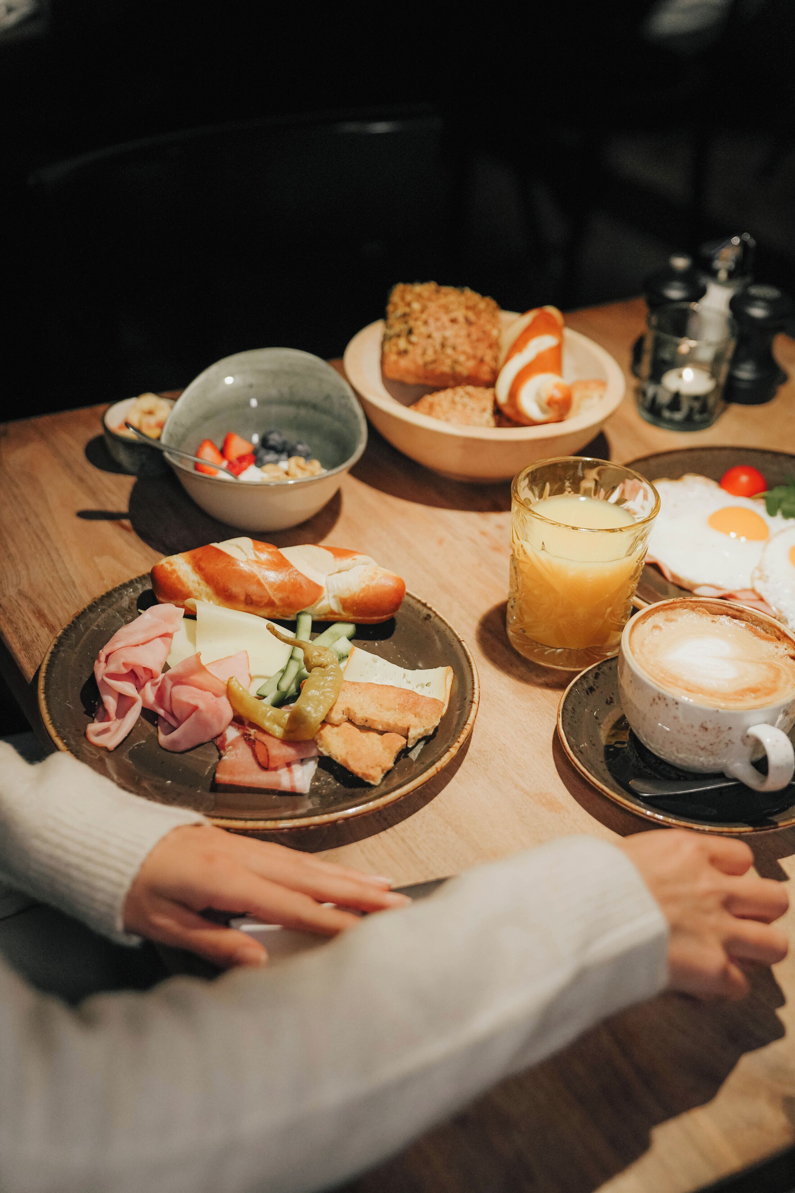 Una mesa de desayuno con diversos alimentos y un vaso de zumo de naranja.