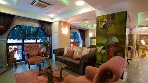 A spacious lobby with a large window, a plush armchair, a sofa, and a glass coffee table. - Zagreb Hotel (Istanbul)