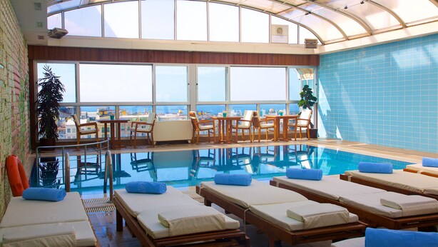 A sunlit indoor swimming pool with lounge chairs and a view of the sea. - Zagreb Hotel (Istanbul)
