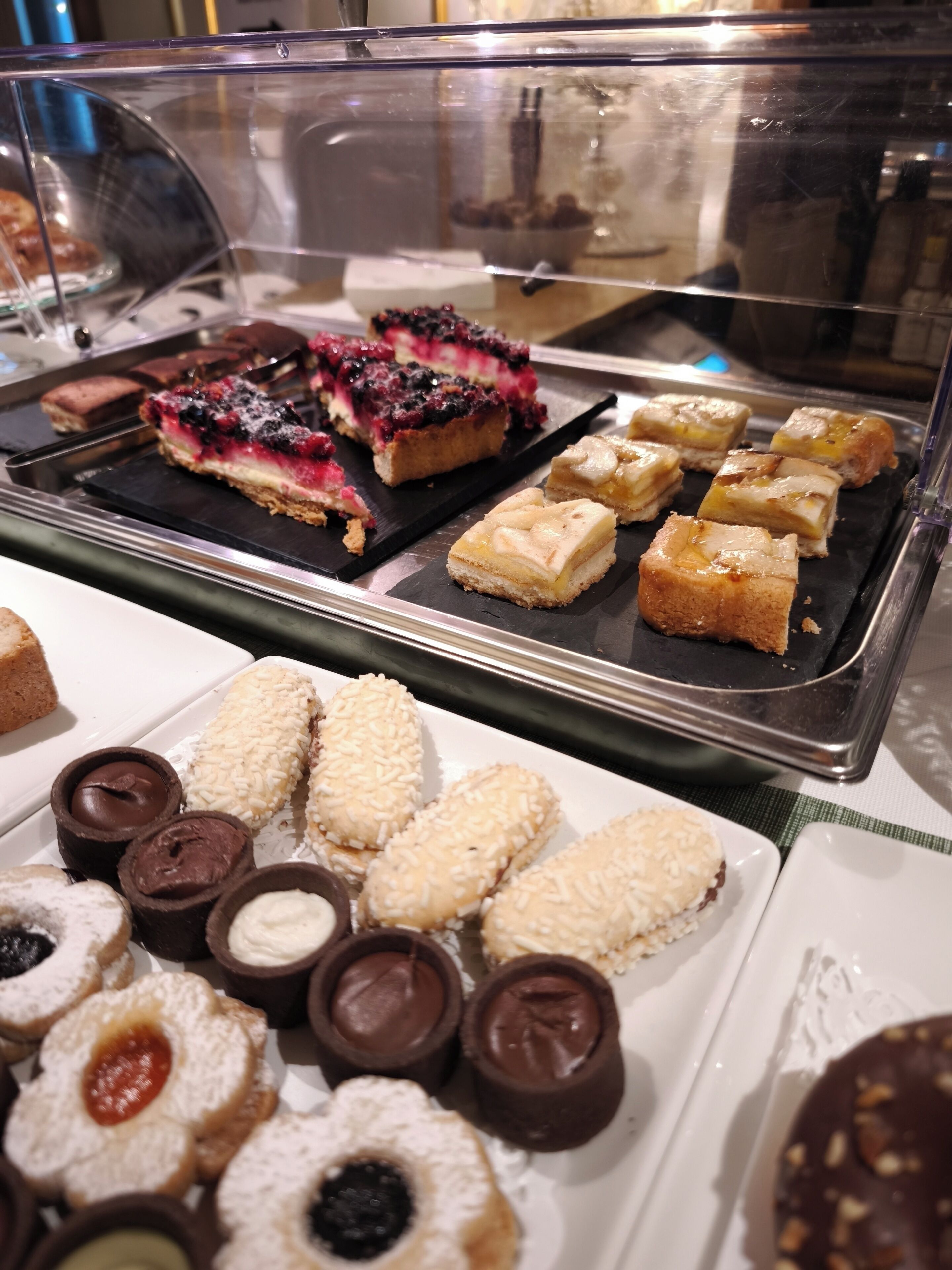 A display case with various pastries and desserts, including blueberry-topped bars and coconut-covered cookies.