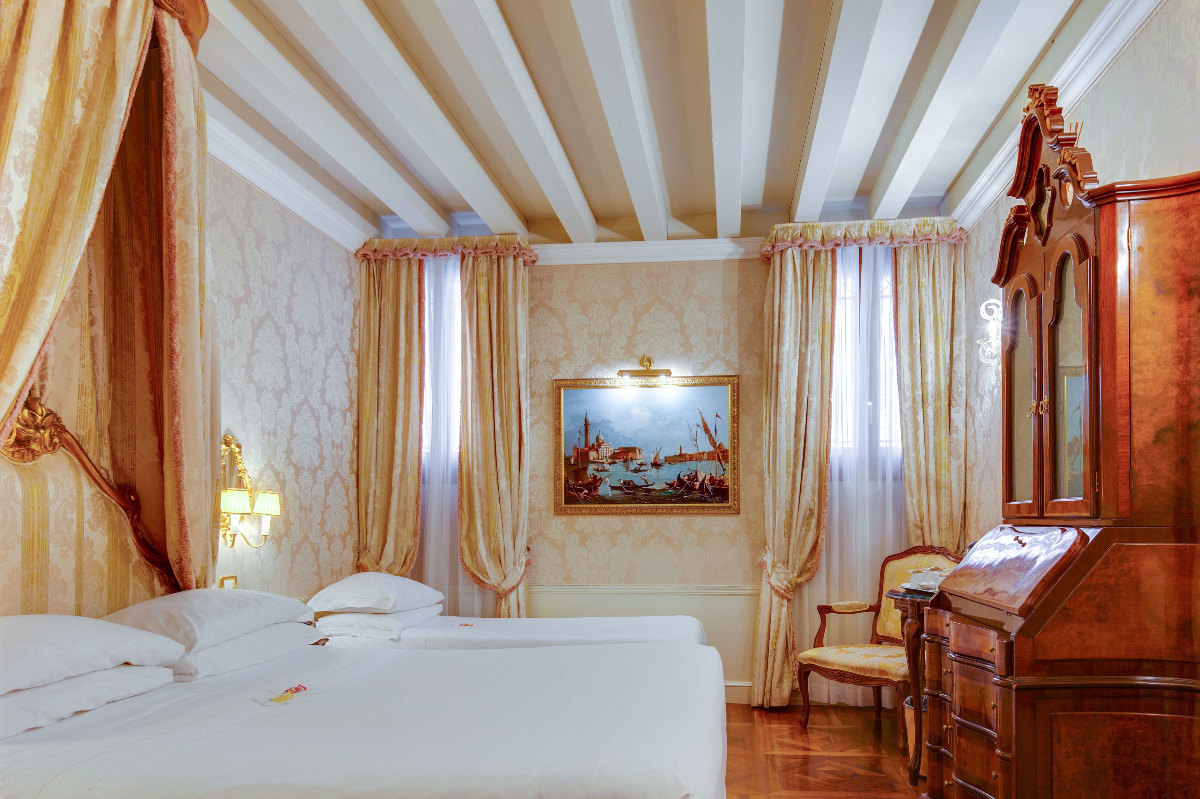 A hotel room with a large bed, a desk, a chair, and a painting on the wall.