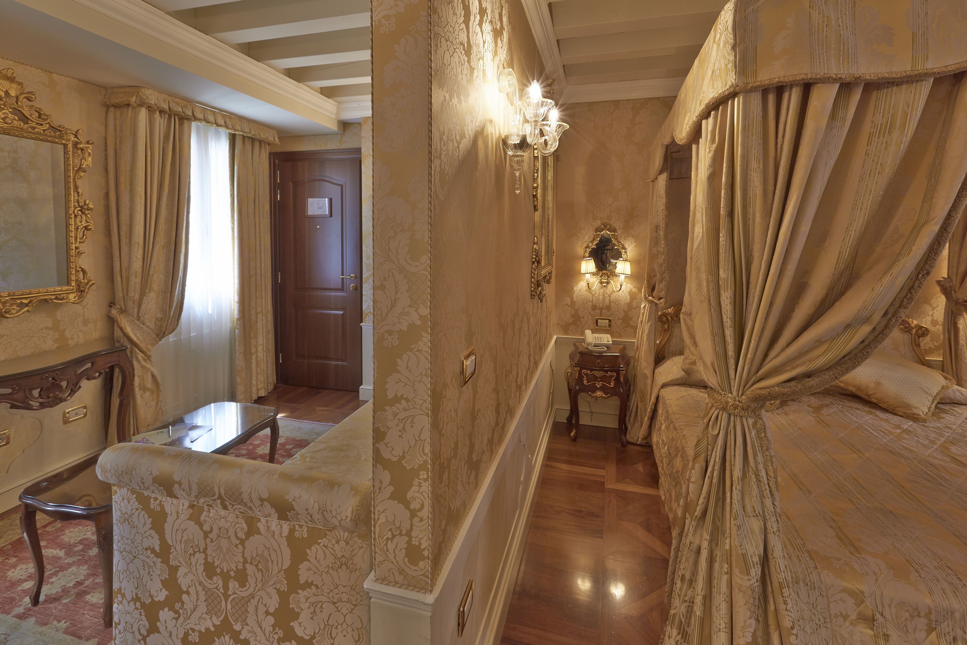 A room with a bed, a chair, a small table, and a mirror.