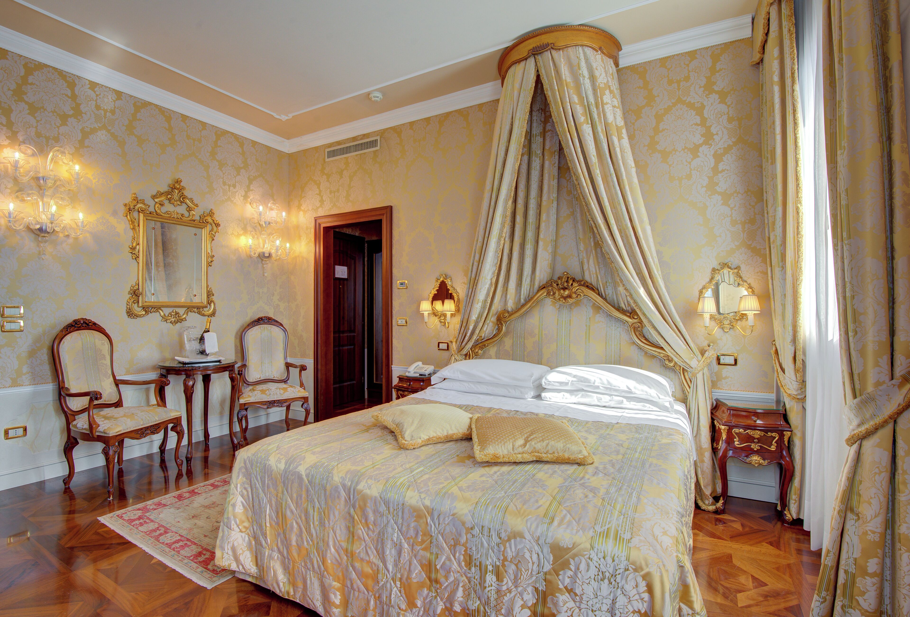 Un dormitorio lujoso con cama con dosel, muebles ornamentales y decoración clásica.