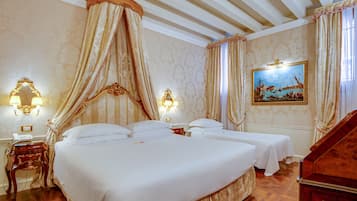 A hotel room with a large bed, two bedside tables, a nightstand, a canopy bed, a painting, and a wooden staircase.