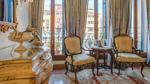 A room with ornate furniture, large windows with curtains, and a view of buildings outside. - Hotel Canal Grande (Venice)