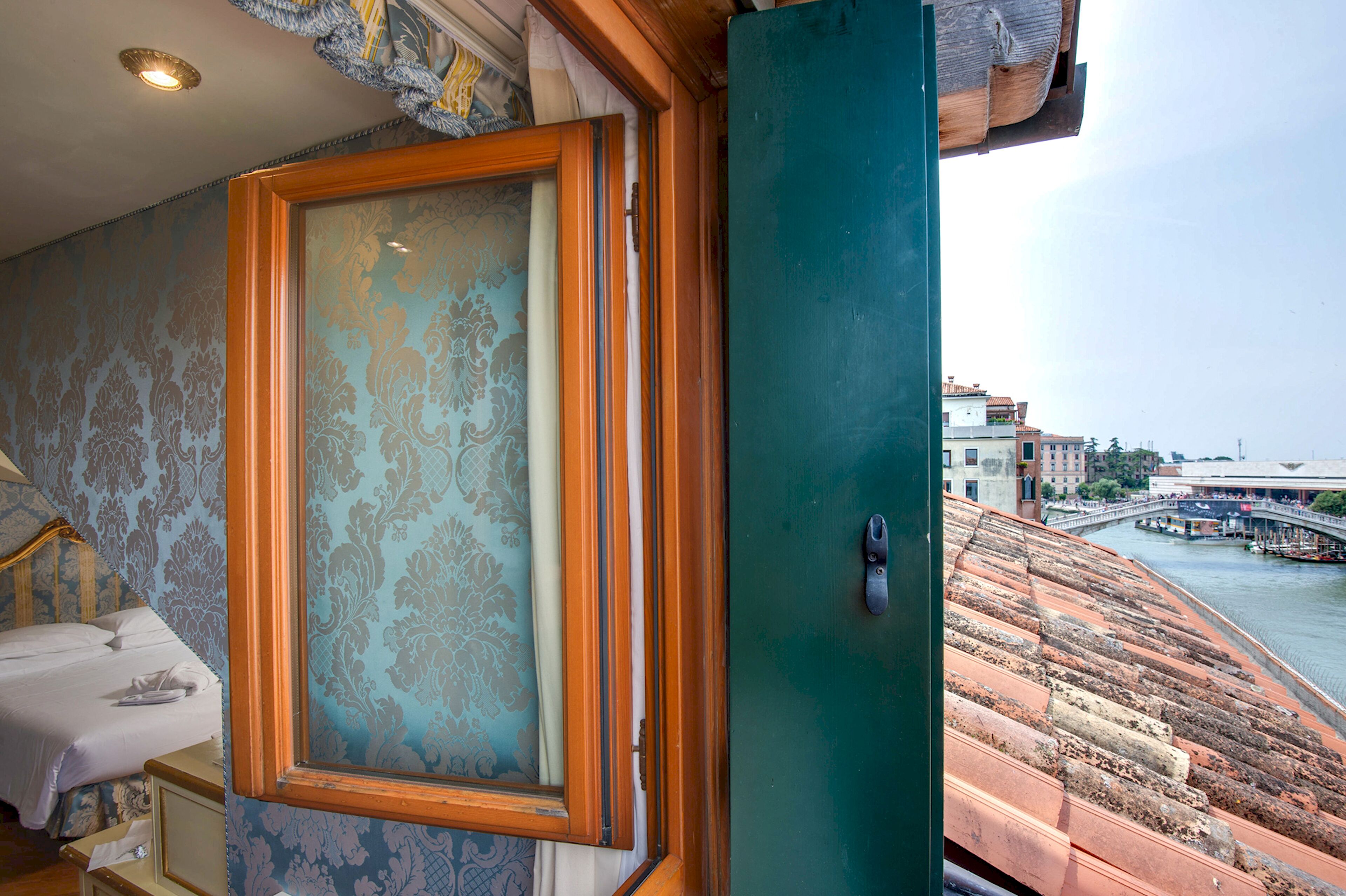 A room with a bed, a window with a view of a river and a bridge, and a door with a handle.