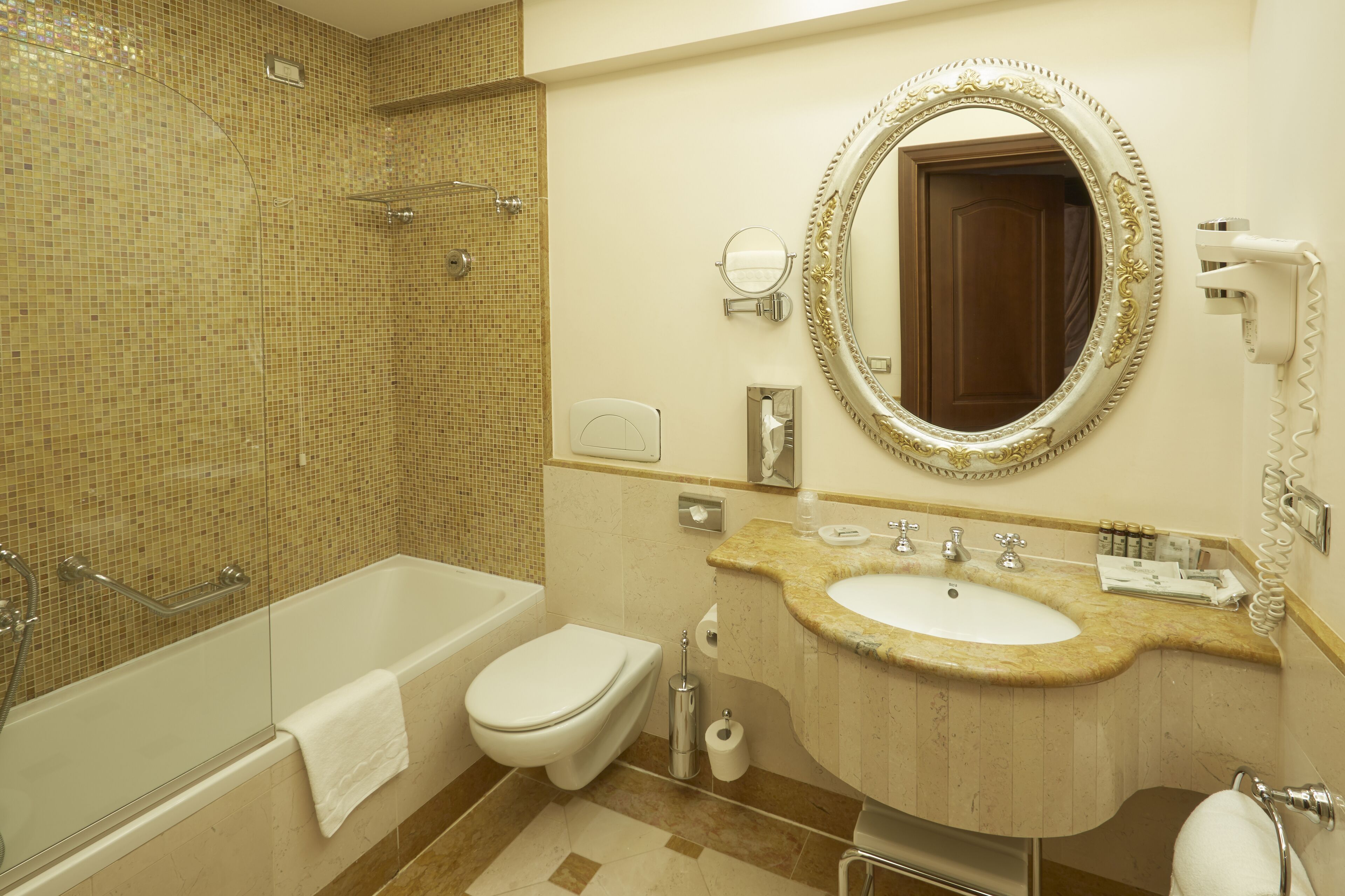 A bathroom with a bathtub, toilet, sink, and a large mirror.