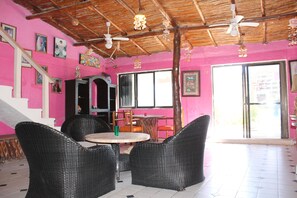 A room with wicker furniture, a ceiling fan, and a staircase.