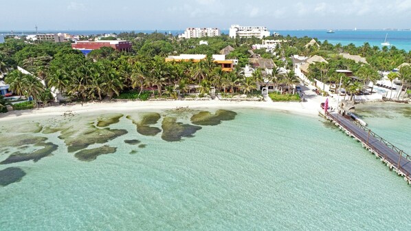Un resort en la playa con aguas turquesas cristalinas, palmeras y un muelle.