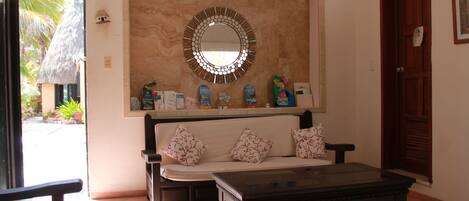 A living room with a sofa, coffee table, and a wall-mounted mirror.