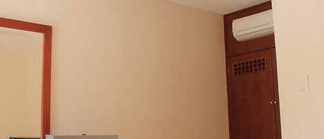 Camera d'albergo con un letto, una scrivania con computer e una sedia, una ventola a soffitto e un condizionatore d'aria.