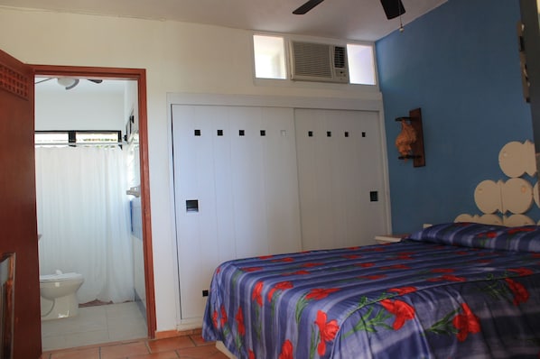 A bedroom with a bed, a wardrobe, and a bathroom visible through an open door. - Hotel Villa Kiin (Isla Mujeres)