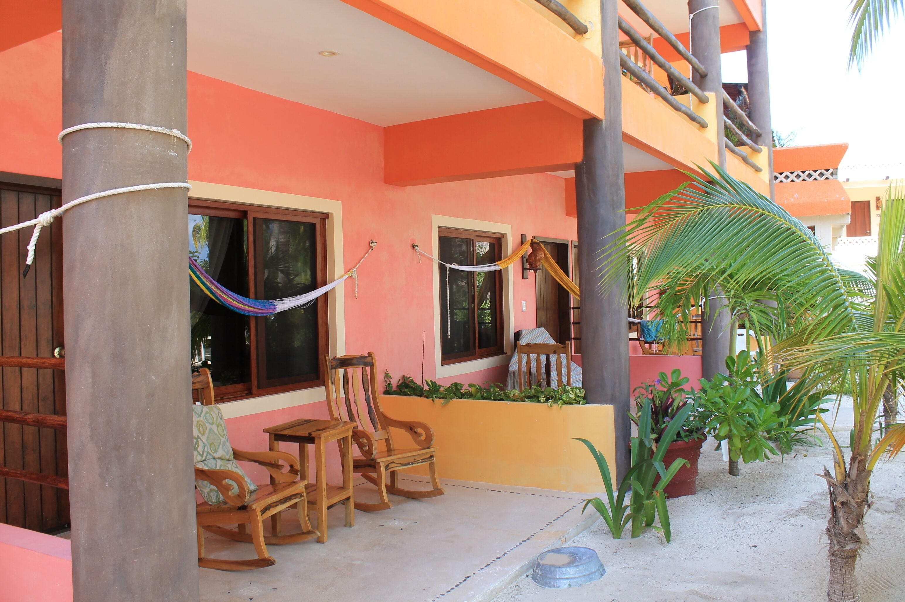 A building with a pink exterior, wooden furniture, and a hammock.