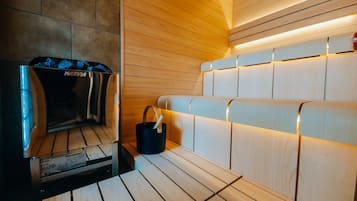 A sauna room with wooden benches and a Harvia sauna unit.