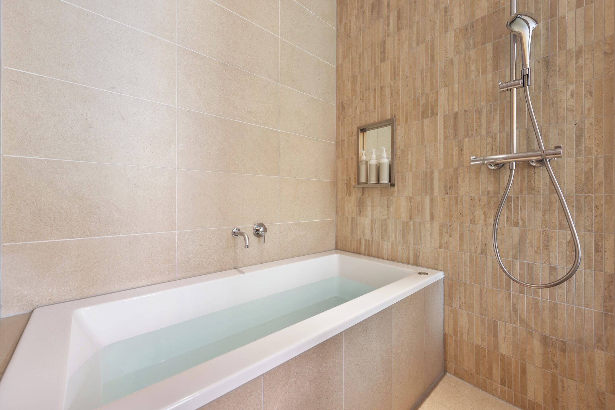 A modern bathroom with a bathtub, a shower, and a mirror.