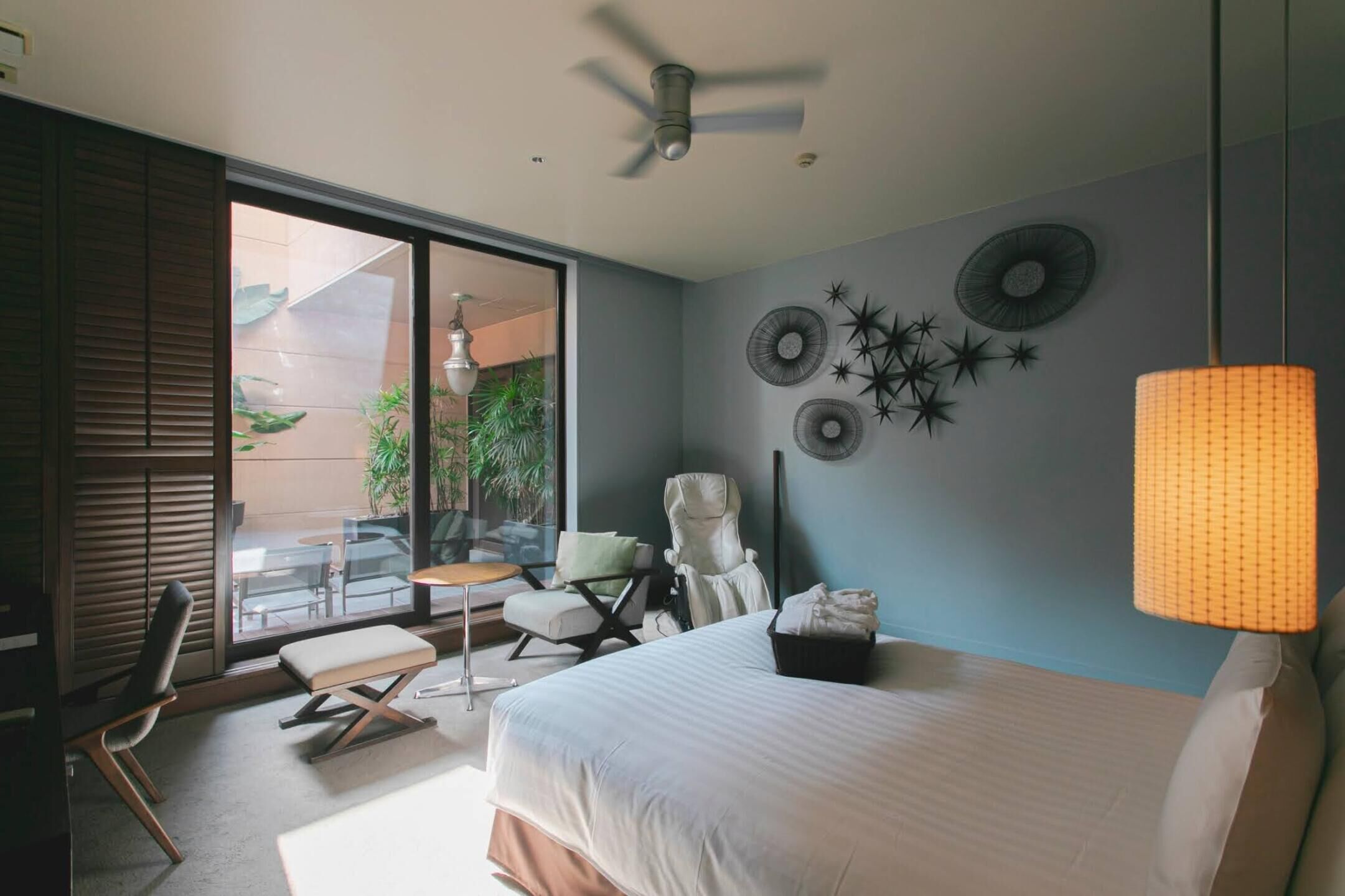 Une chambre moderne avec un lit, un coin salon comprenant une table et des chaises, et un balcon agrémenté de plantes.