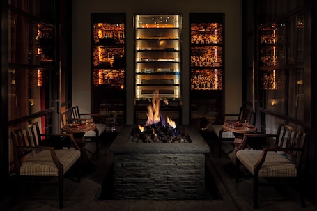 A cozy seating area with a stone fire feature, wooden chairs, and a central table.