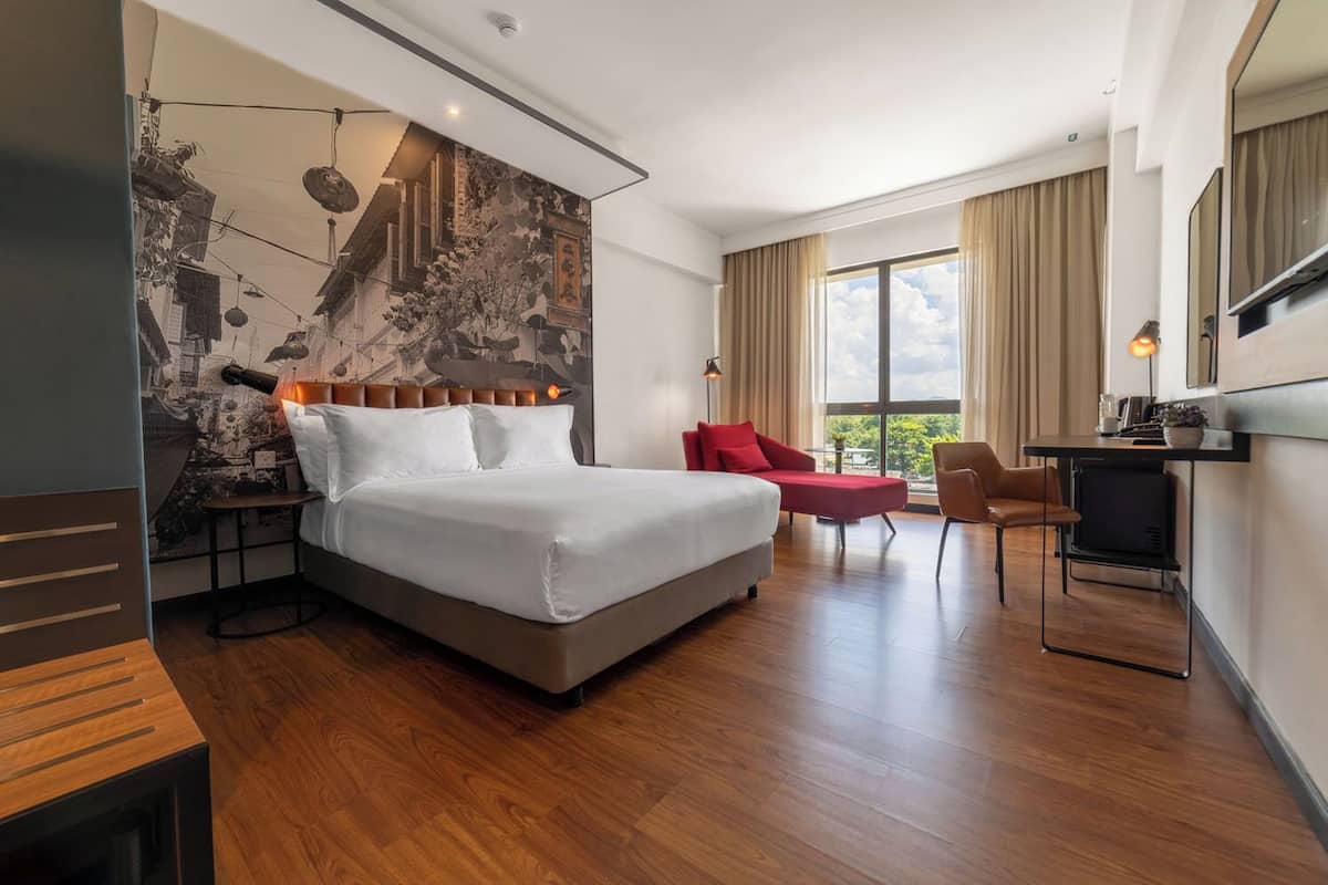 Una habitación de hotel moderna con una cama grande, un escritorio, una silla y un televisor.