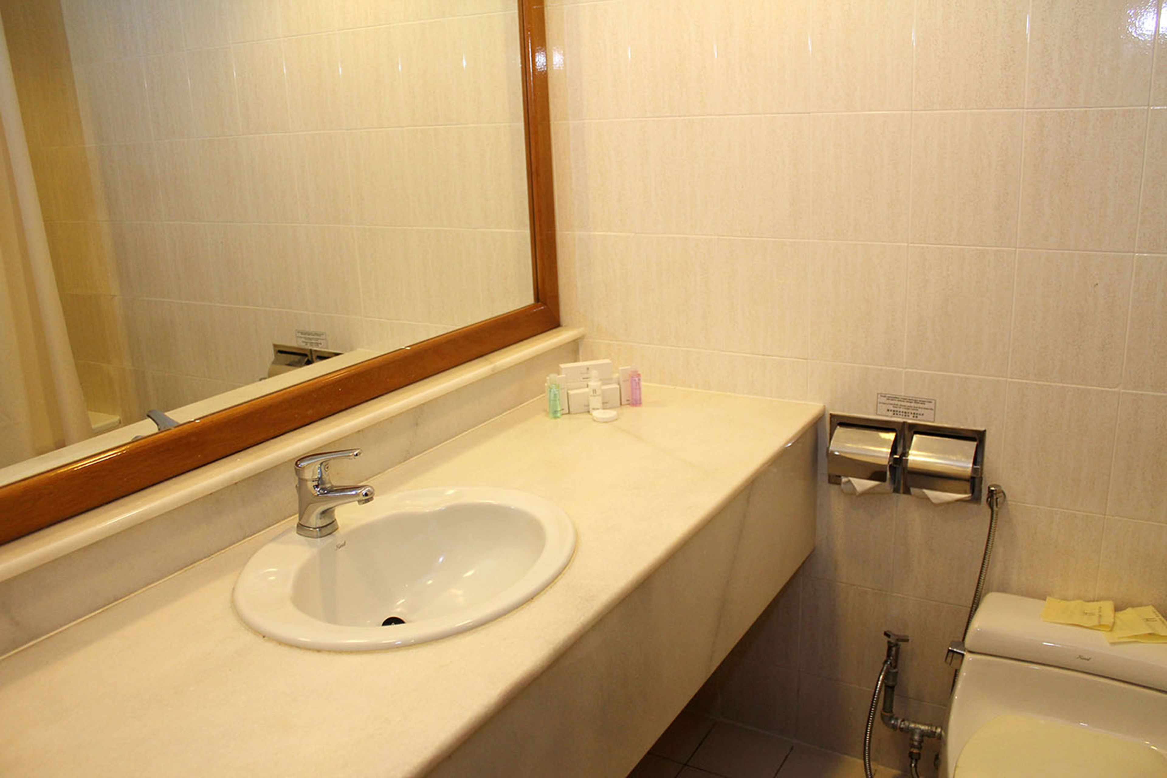 A bathroom with a white sink, mirror, and toilet.