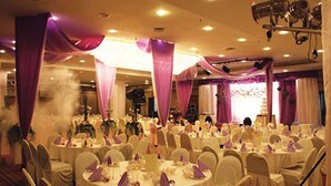 A banquet hall with round tables covered in white tablecloths and purple drapes, equipped with chairs and centerpieces. - Travelodge Ipoh (Ipoh)
