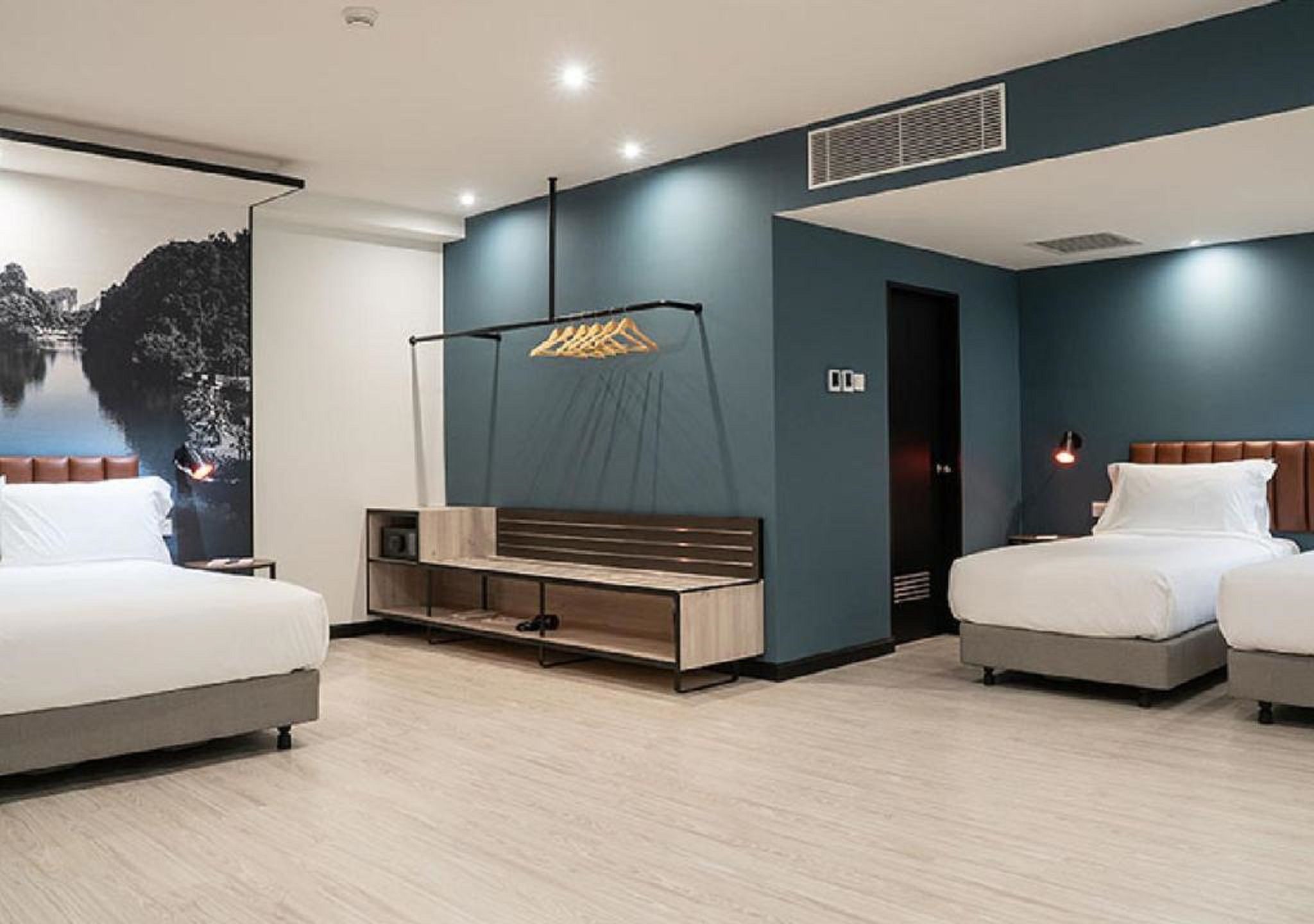 Une chambre d’hôtel moderne avec deux lits, un banc en bois, un téléviseur fixé au mur et une grande fenêtre donnant sur un paysage montagneux.