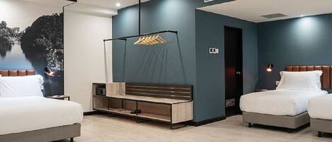 Une chambre d’hôtel moderne avec deux lits, un banc en bois, un téléviseur fixé au mur et une grande fenêtre donnant sur un paysage montagneux.