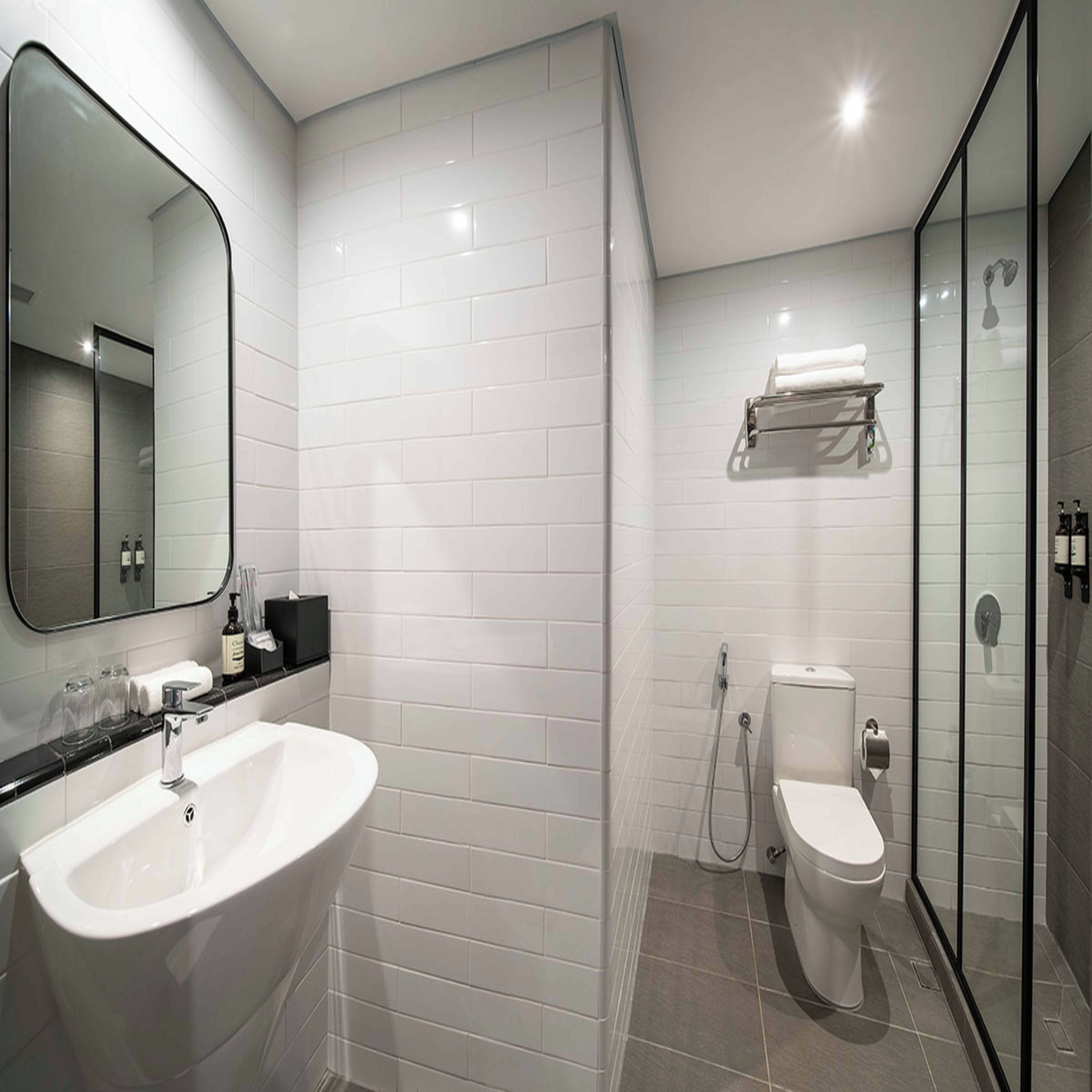 A modern bathroom with a white sink, a toilet, and a glass shower enclosure.