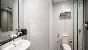 A modern bathroom with a white sink, a toilet, and a glass shower enclosure.
