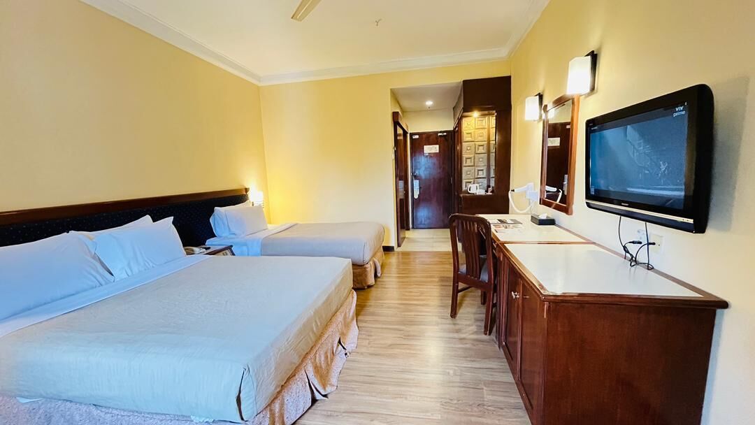 A hotel room with two beds, a desk with a chair, a television, and a mirror.