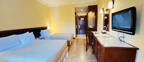 A hotel room with two beds, a desk with a chair, a television, and a mirror.