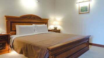 Cama bem arrumada com cabeceira de madeira, luminária de cabeceira e quadro na parede.