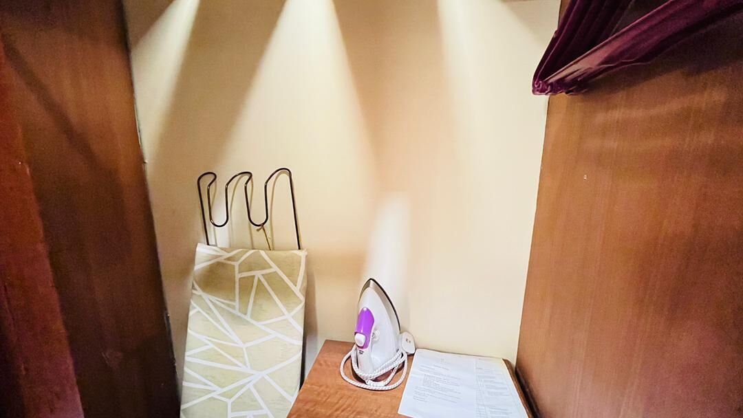 A small wooden table with an iron and a white paper holder with utensils.