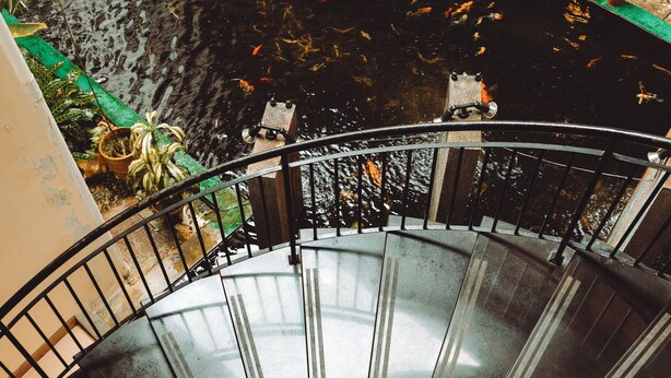 A spiral staircase with a view of a koi pond and potted plants. - Heritage Hotel Cameron Highlands (Tanah Rata)